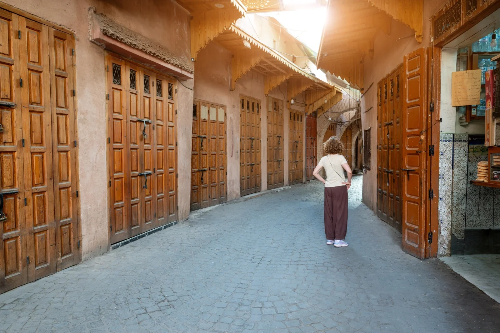 A person standing in a quiet passage lined with closed wooden doors.